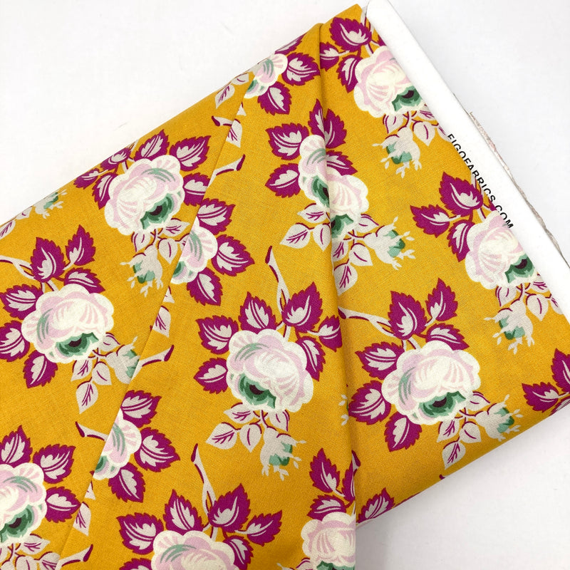 A golden yellow quilting cotton fabric with white, green, and magenta floral designs.