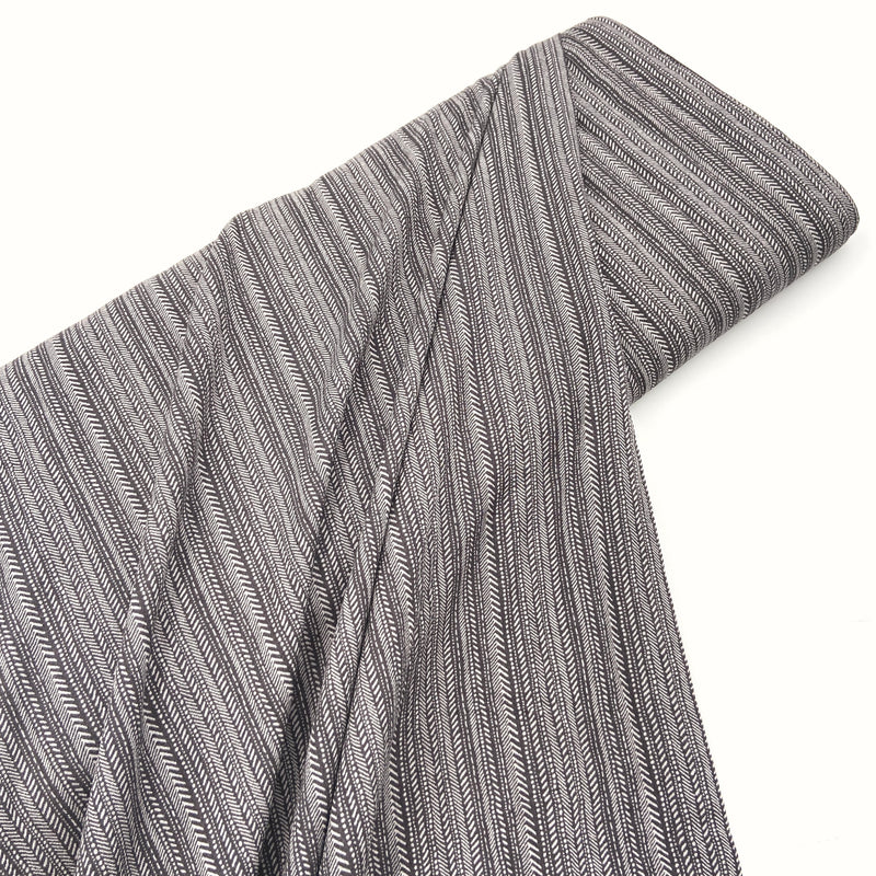 A bolt of gray striped fabric laying on a white table. 