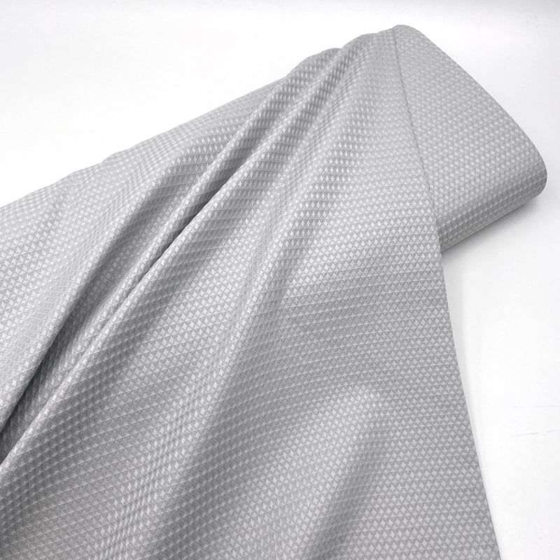 A bolt of grey waffle weave fabric sitting on a white table.