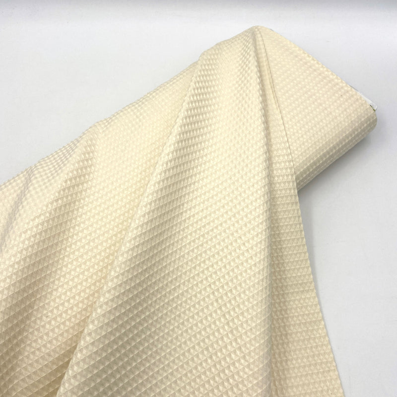 A bolt of cream-colored waffle weave fabric made from organic cotton. 