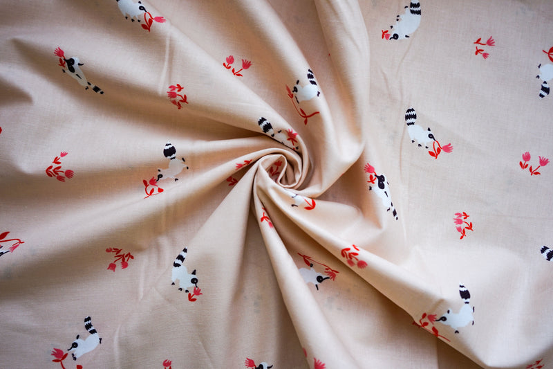 light pink quilting cotton fabric scrunched in a swirl with small white raccoons sniffing little pink flowers