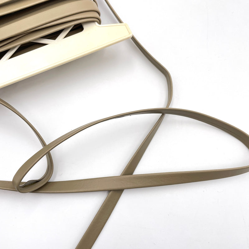 A bolt of light brown faux leather trim laying on a white table.