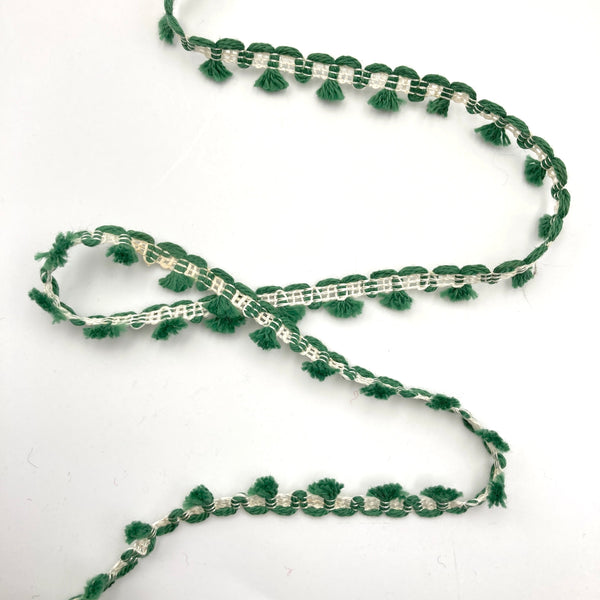 green and white decorative trim laying on a white table in a swooping pattern